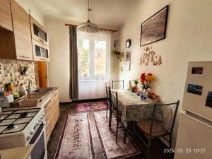 a kitchen with a table with chairs and a window at Karancs Apartman Salgótarján in Salgótarján