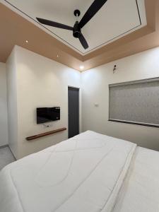a bedroom with a white bed and a ceiling fan at Hotel Amora in Dighori Buzurg