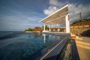 a swimming pool in front of a house with the ocean at Villa Pantheon with Private Pool & Jacuzzi in Pomos