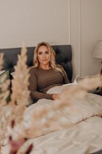 a woman sitting in bed reading a book at Boutique Vaksali Apartment in Viljandi