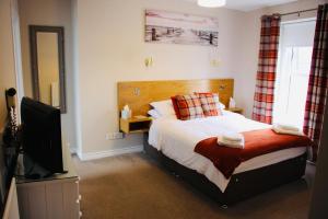 a bedroom with a bed and a flat screen tv at Central Bar Guesthouse in Cushendall