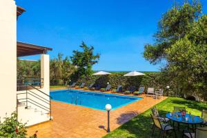 a swimming pool in a yard with chairs and tables at Villa Anna Maria by Villa Plus in Pírgos Psilonérou