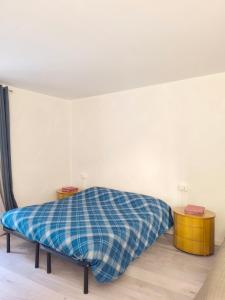 a bed with a blue plaid blanket in a room at Levico Antiche Terme Apartment in Levico Terme