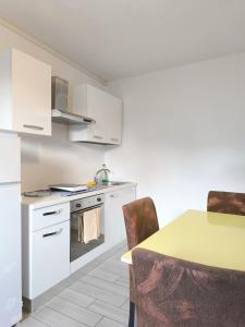 a kitchen with white cabinets and a table with chairs at Levico Antiche Terme Apartment in Levico Terme +8 photos