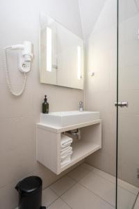 a white bathroom with a sink and a mirror at Hotel Zeerust in De Koog