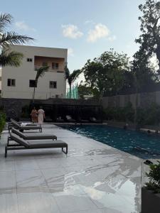 a swimming pool with people walking in front of a building at Nomah Homes The Bantree in Accra