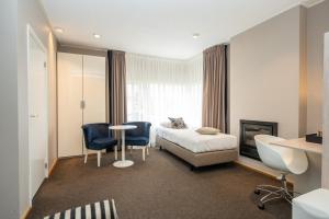 a hotel room with a bed and a table and chairs at Hotel Zeerust in De Koog
