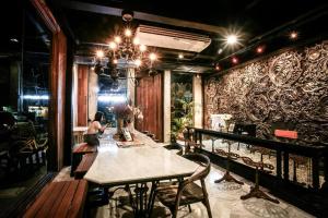 a woman sitting at a table in a room at Shade House - Phuket Downtown in Phuket