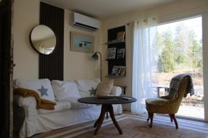 a living room with a white couch and a table at Schwedisches Waldcottage Fluss & Wanderwege in Fristad