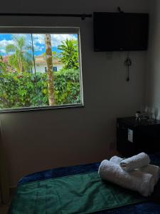 a bedroom with a bed with a large window at Pousada Oxente Uai! in Pirenópolis