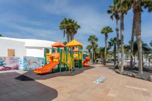 a playground with slides and palm trees in a park at Oasis Duna _ Casa Mate Pool in Corralejo