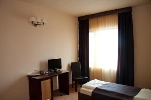Habitación de hotel con cama, escritorio y ventana en Hotel Hanul de la Rascruce, en Arad
