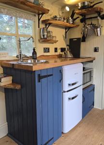 a kitchen with blue cabinets and a sink at Firbank Park Shepherd Huts in Dinnet