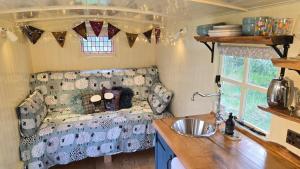 a caravan with a couch and a sink in a kitchen at Firbank Park Shepherd Huts in Dinnet