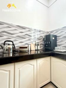 a kitchen with white cabinets and a black counter top at The Single Level Bliss By Nestcove in Malacca