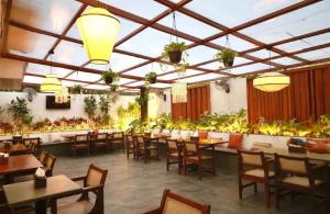 a restaurant with tables and chairs and plants at Hotel Pune Pride, Baner in Pune