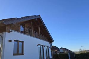 a white house with a balcony on top of it at Schöne moderne Ferienwohnung-Balkon-Fahrradparkplatz-Wallbox in Hürtgenwald