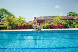 a woman and two children standing next to a swimming pool at The International Centre Goa in Panaji