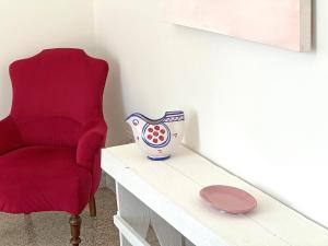 a red chair sitting next to a table with a vase at Villa Ipomea - Terra Suite in Salerno