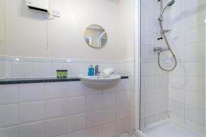a white bathroom with a sink and a shower at Stylish 2-Bed Manning Gardens in South Norwood +15 photos