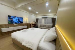 a bedroom with a large white bed and a television at Shade House - Phuket Downtown in Phuket