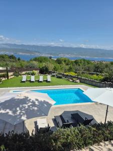 a swimming pool with umbrellas and chairs next to a resort at House Erika in Šilo