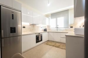a kitchen with white cabinets and a stainless steel refrigerator at Sinani Apartment - Sea View Balcony & Jacuzzi Gem in Asgourou +5 photos