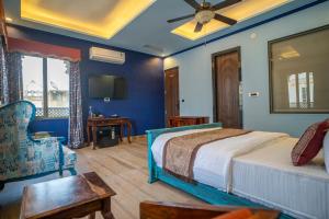 a bedroom with a bed and a chair and a tv at UDAISA - The Luxury Art in Udaipur