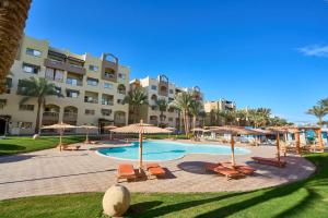 a resort with a swimming pool with chairs and umbrellas at Studio at El Karma Beach & Aqua Park in Hurghada