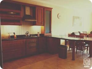 a kitchen with wooden cabinets and a table and a dining room at Comfy & Spacious 1BDR 3 Min to Beach in Marsalforn