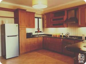 a kitchen with wooden cabinets and a white refrigerator at Comfy & Spacious 1BDR 3 Min to Beach in Marsalforn
