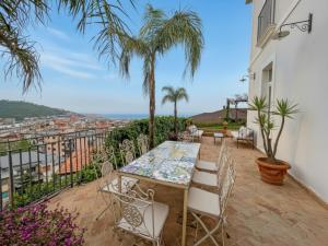 a patio with a table and chairs and palm trees at Villa Ipomea - Terra Suite in Salerno