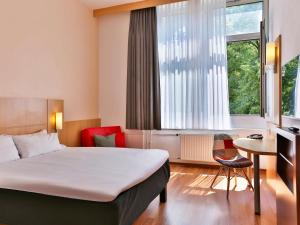 a hotel room with a bed and a desk and a window at ibis Berlin City Süd in Berlin +30 photos