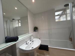 a white bathroom with a sink and a shower at Central Stow Bakehouse Flat in Stow on the Wold