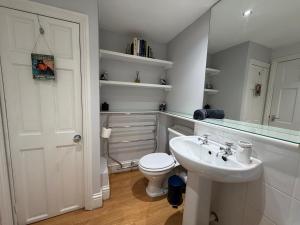 a white bathroom with a toilet and a sink at Central Stow Bakehouse Flat in Stow on the Wold
