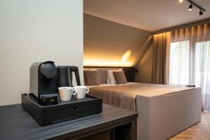 a hotel room with a bed with two cups on a table at Hotel het Uilenbos in De Koog