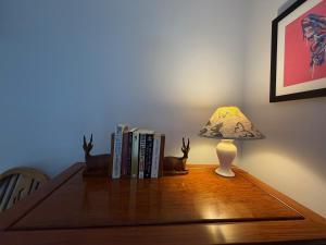 a table with a lamp and books on it at Central Stow Bakehouse Flat in Stow on the Wold +9 photos