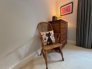 a chair with a pillow on it next to a dresser at Central Stow Bakehouse Flat in Stow on the Wold
