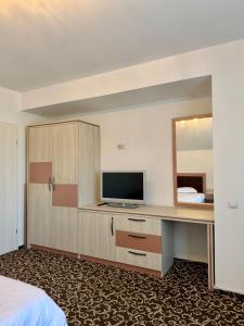 a hotel room with a desk with a tv and a mirror at ILSA Properties in Craiova +10 photos