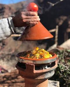 a person is holding up a red object on top of a bell at Green Valley Lodge - Atlas Mountains Nature in Taroudant