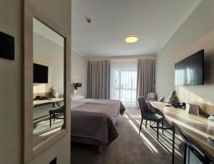 a hotel room with a bed and a desk at Hotel Aurora Family & SPA in Międzyzdroje