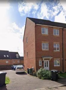 a brick building with a car parked in a parking lot at Gem Relax in Leighton Buzzard
