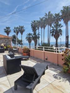 a patio with tables and chairs and palm trees at Vela Bianca H & R in Diano Marina