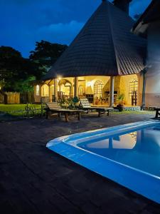 a gazebo with benches and a swimming pool at night at Kitunduni Lodge in Arusha