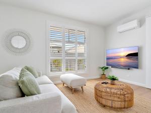 a white living room with a couch and a table at Lillian Waters Retreat in Yamba