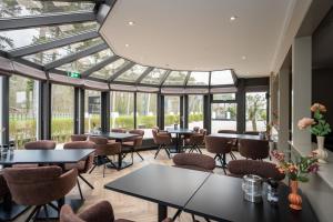 a restaurant with tables and chairs and windows at Hotel het Uilenbos in De Koog +16 photos