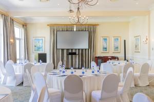Ein Konferenzraum mit weißen Tischen und Stühlen sowie einer Projektionsfläche in der Unterkunft The Beach Hotel in Port Elizabeth + 158 Fotos