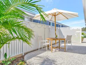 a table and chairs with an umbrella next to a fence at Lillian Waters Retreat in Yamba