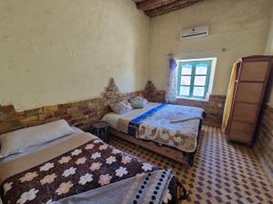 a bedroom with two beds and a window at Auberge camping la tradition in Merzouga