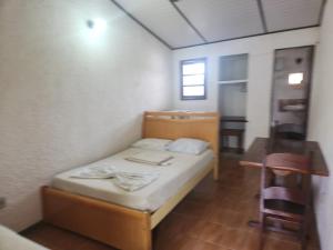 a small room with a bed and a table at Solemar in Guarapari